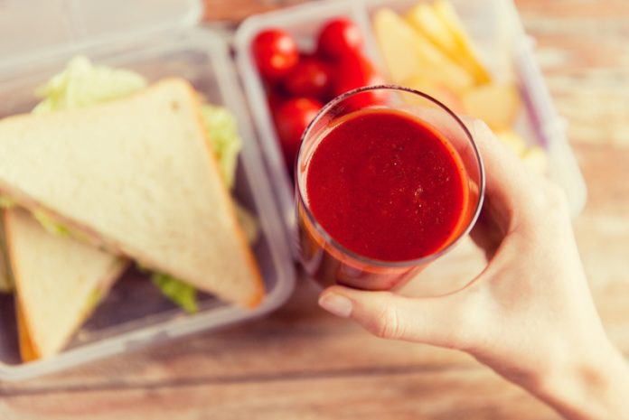 close up of woman hand holding tomato juice glass